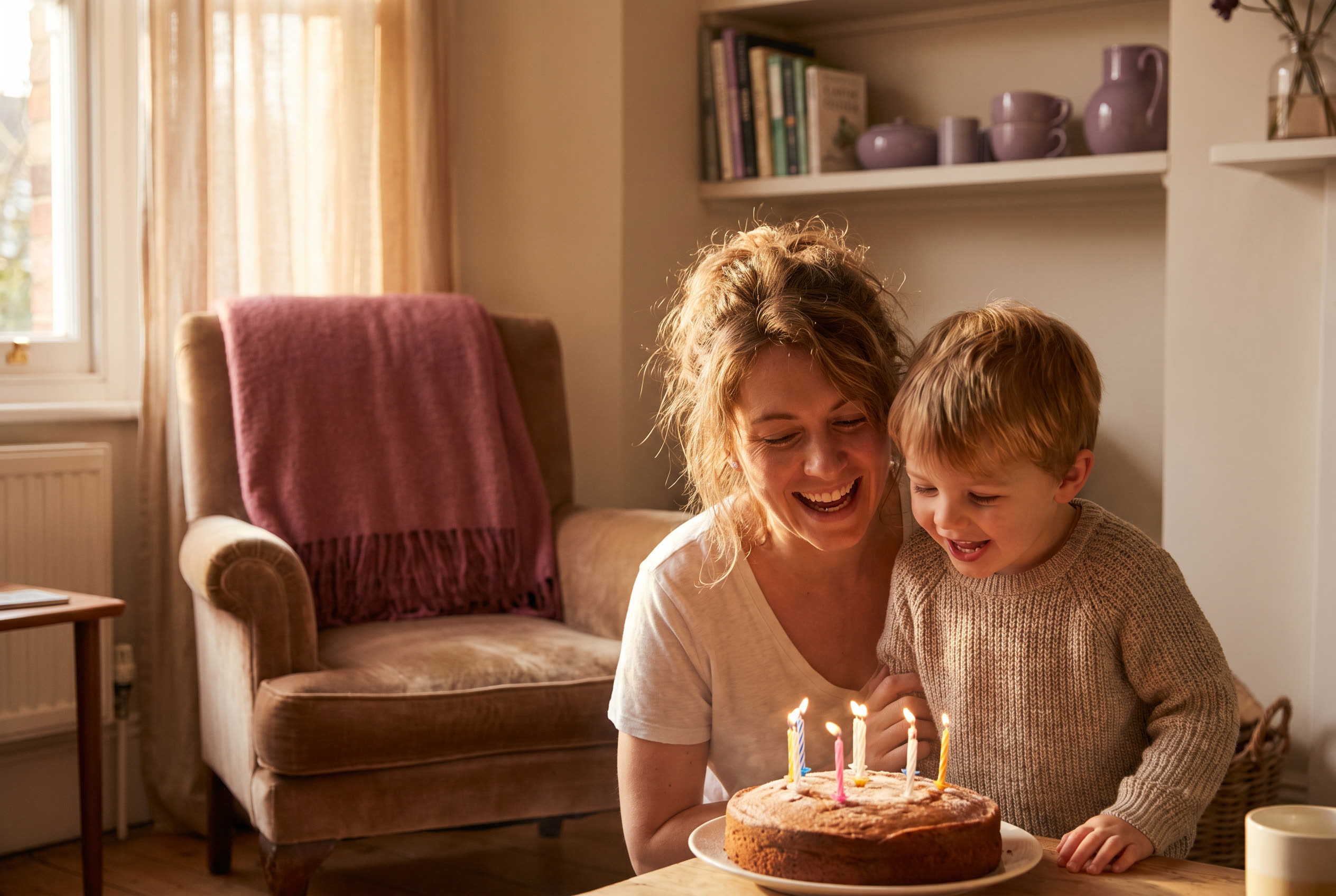 A person and their son sharing a joyful birthday moment at home