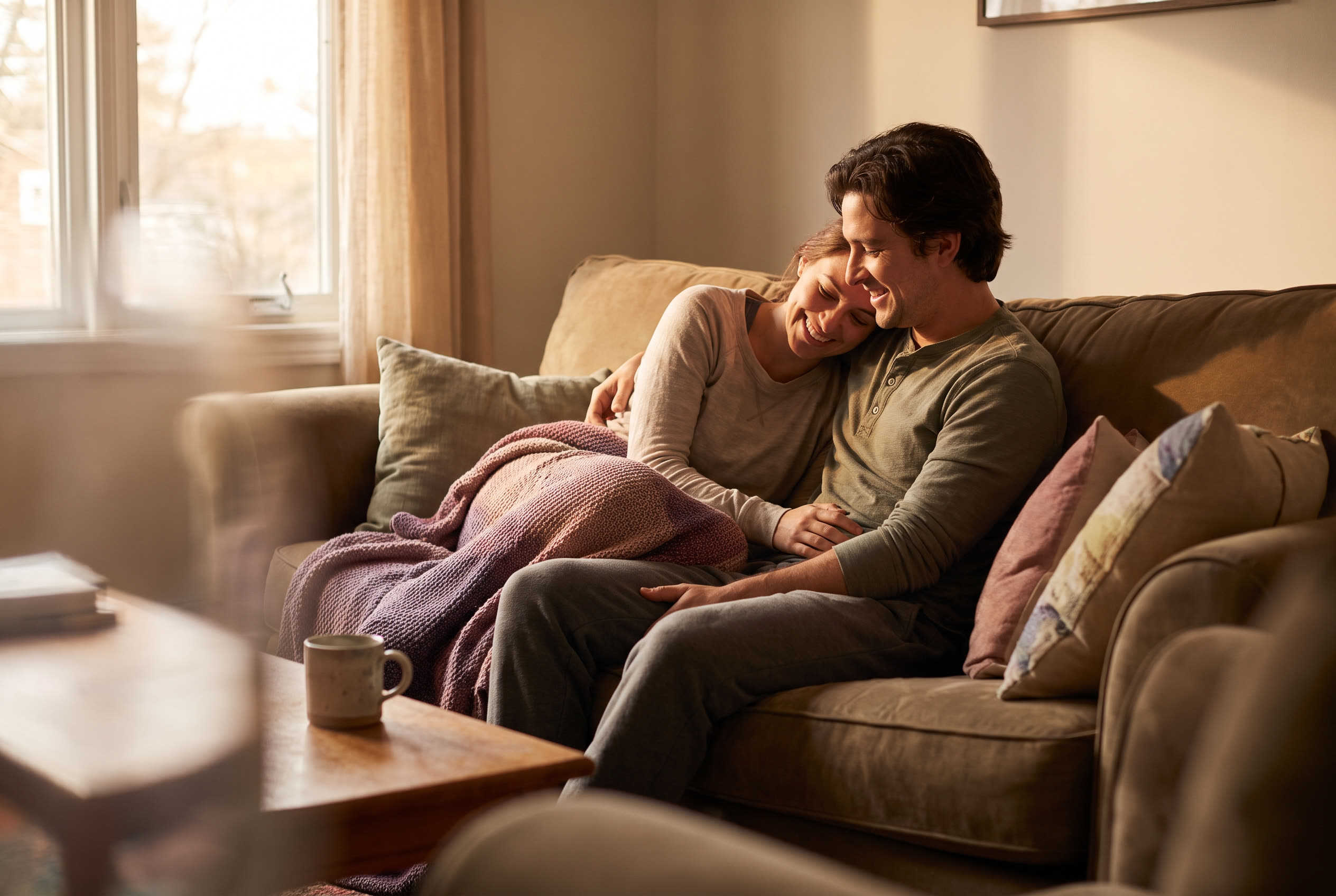 A couple sharing a warm everyday moment at home, spontaneous tenderness, no special occasion