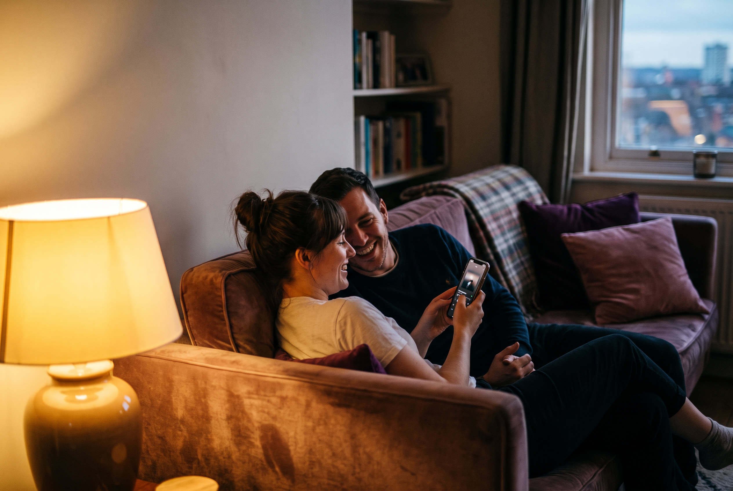 A person playing a song from a smartphone for their husband, both smiling, an ordinary evening made special