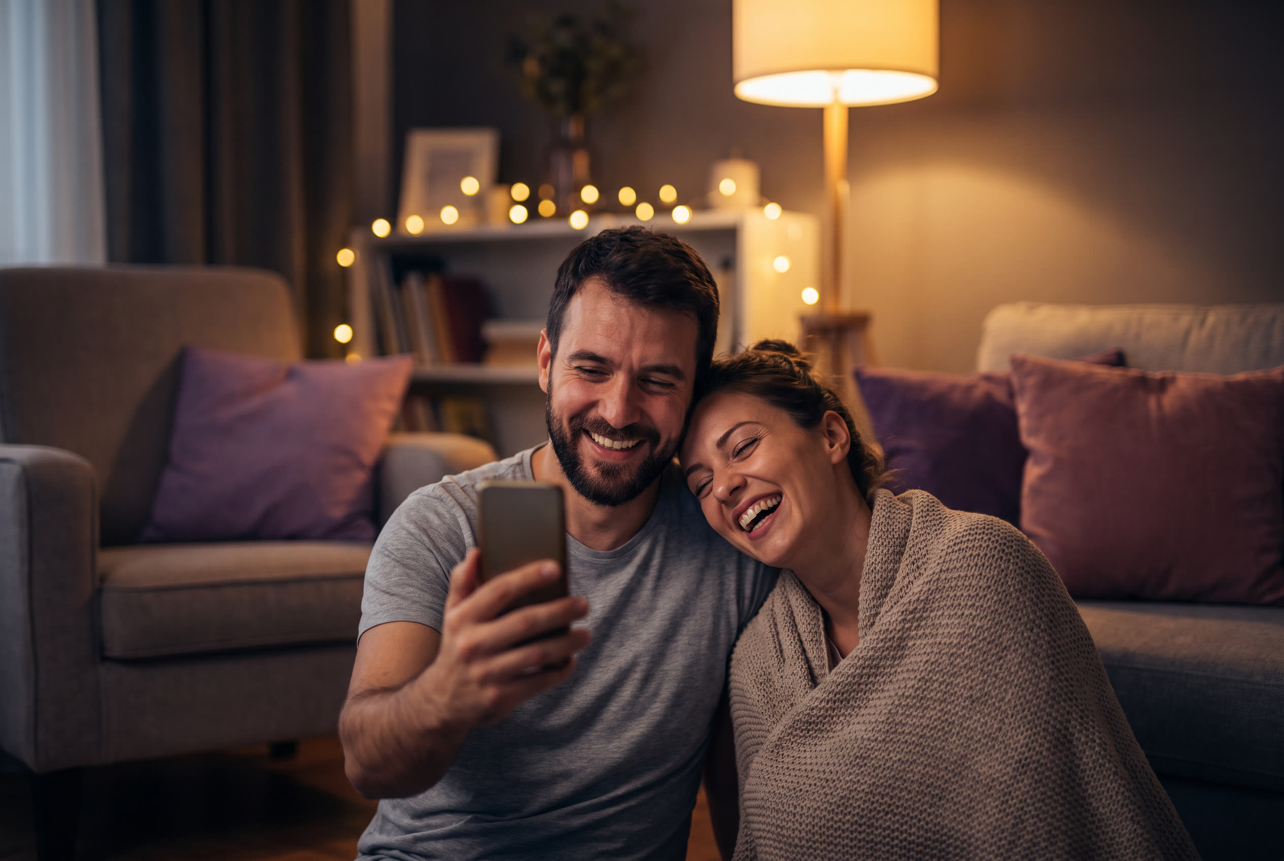 A person playing a song from a smartphone for their wife, both smiling, an ordinary evening made special
